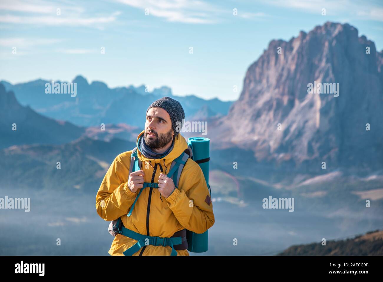 Jeune homme randonnée au sommet de la montagne de Seceda. Sac à dos, veste jaune, bottes, bonnet. Voyageant à, puez Odle, Trentino Dolomites, Italie. Banque D'Images