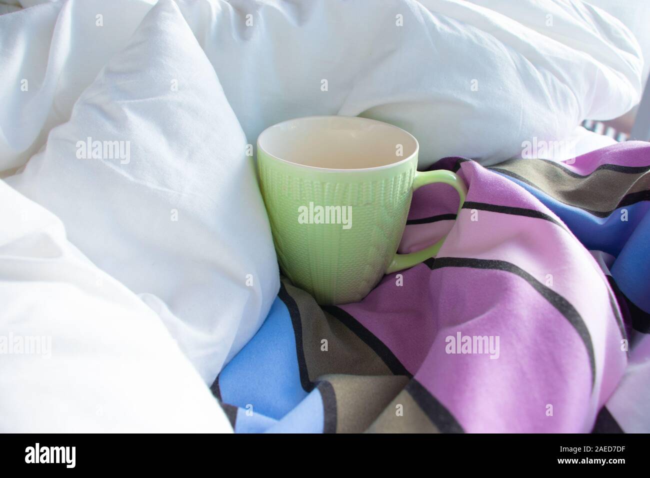 Bol vert dans le lit avec couverture blanche à rayures et couette Banque D'Images