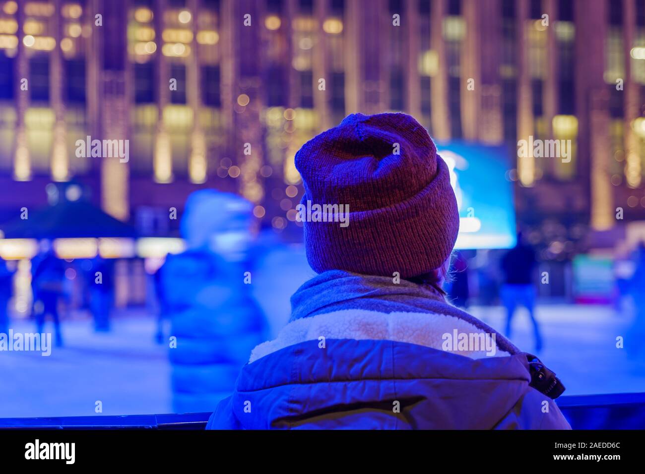 Garçon avec chapeau de ski et veste d'hiver montre les gens profiter du patinage sur glace temporaire à Düsseldorf pendant le marché de Noël. Banque D'Images