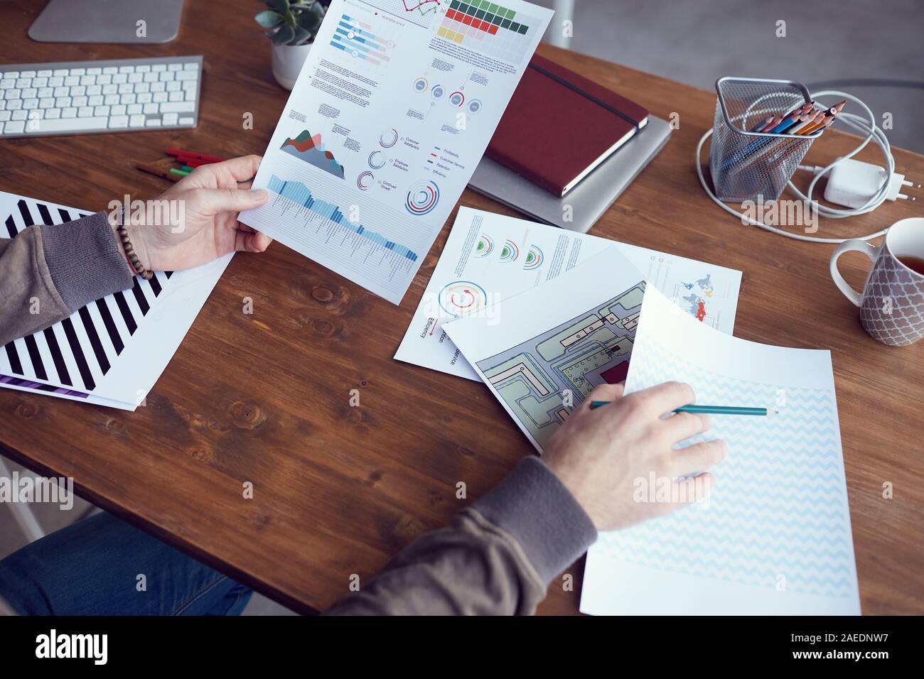 Gros plan du portrait moderne méconnaissable rapport statistique avec des données de couleur tout en travaillant au bureau dans un bureau en bois, copy space Banque D'Images