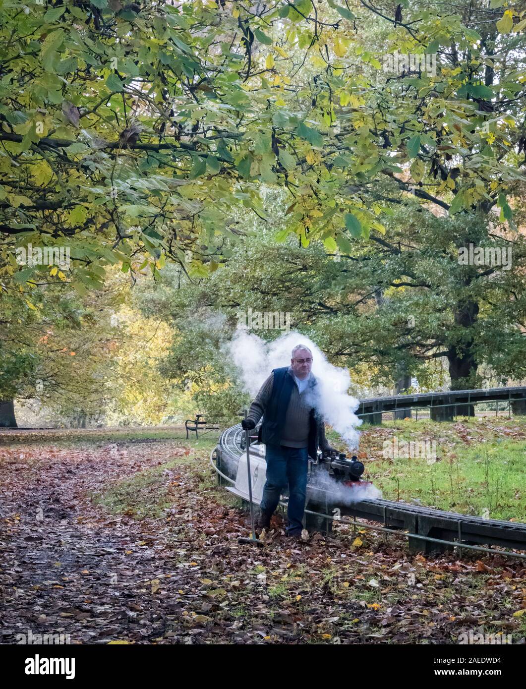 Un train à vapeur miniature avec le conducteur marchant à côté de Mote Park, Maidstone, Kent, UK Banque D'Images