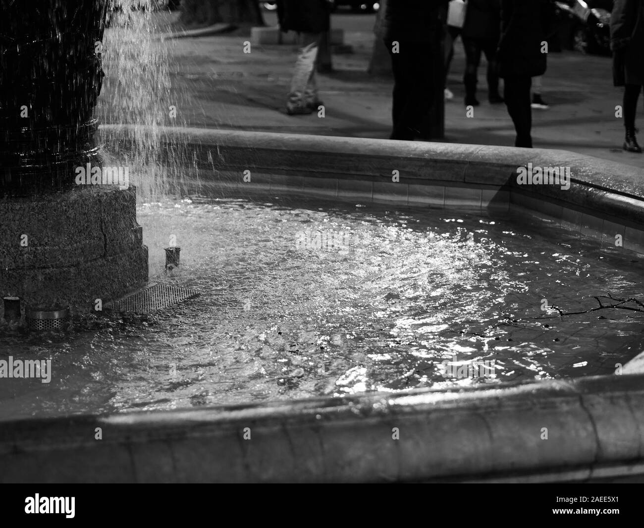 Close-up of Water fountain et belle réflexion sur la surface de l'eau de nuit à Sloan Square, Londres, Royaume-Uni. Image en noir et blanc. Banque D'Images
