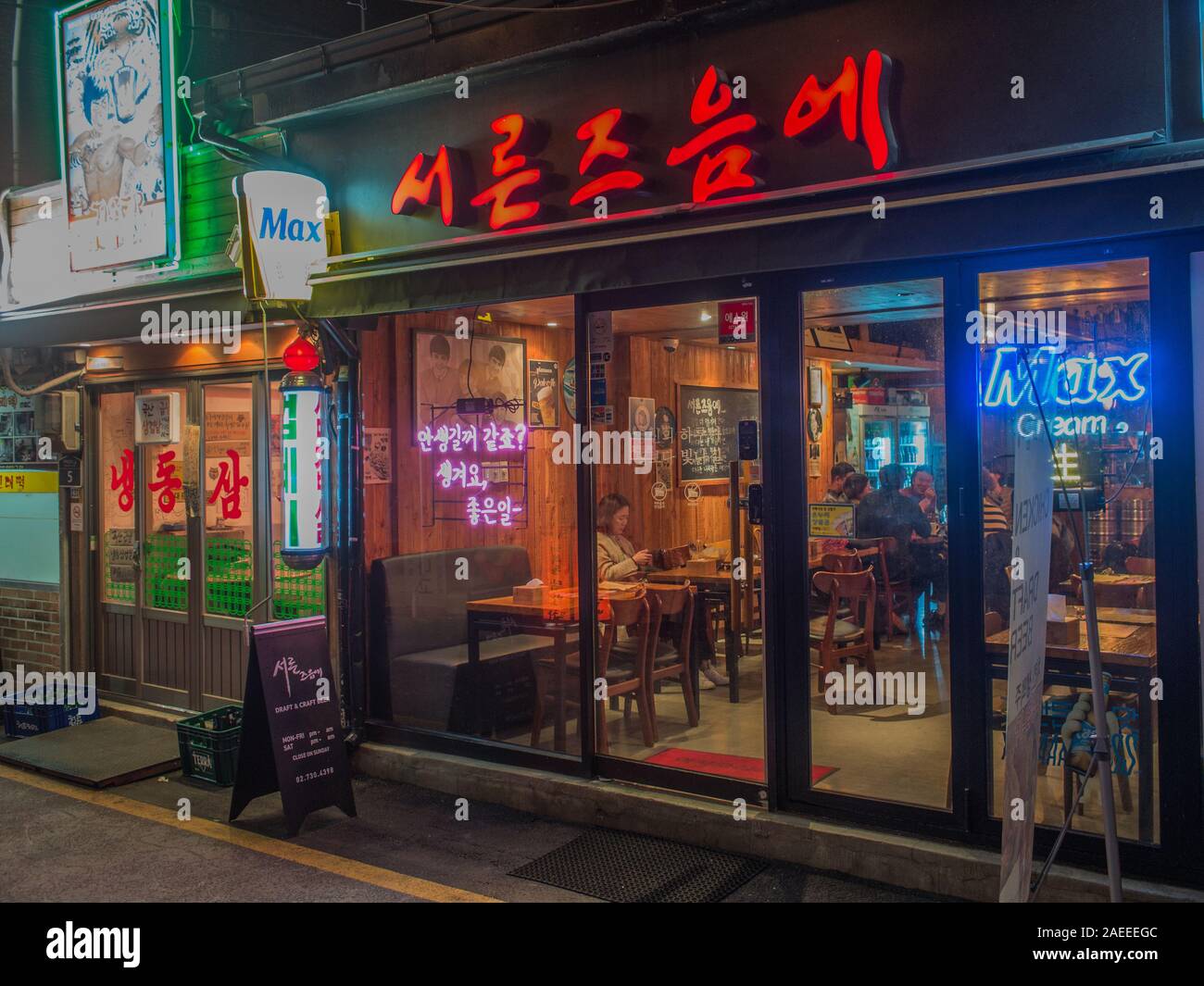 Les gens dans le bar, fenêtre avec des enseignes au néon et lettres hangul, nuit, à proximité de la station de Gyeongbokgung, Séoul, Corée du Sud. Banque D'Images