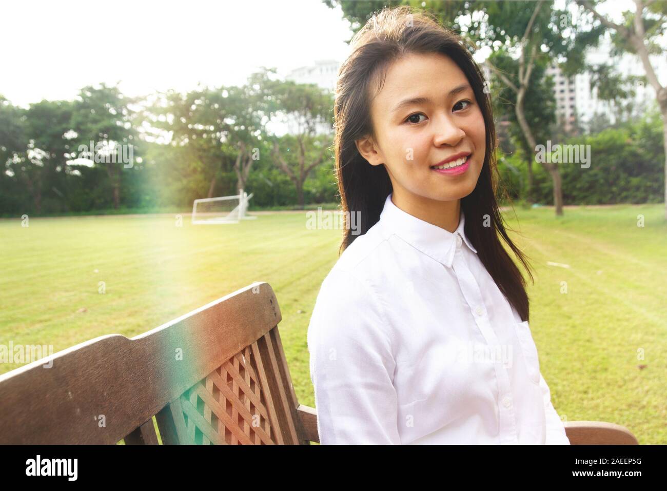 Portrait of young student smiling sitting at outdoor sous la lumière du soleil sur le greenfield en l'université Banque D'Images