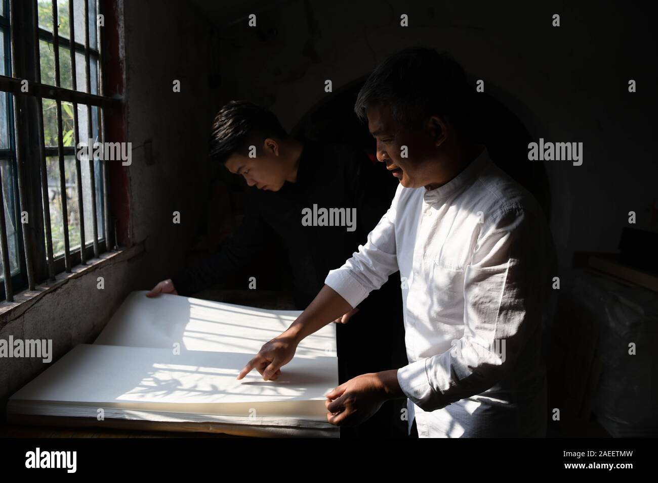 (191209) -- JINGXIAN, le 9 décembre 2019 (Xinhua) -- Cao Jianqin (R) et son fils Cao Li vérifier la qualité de papier à l'Zijinlou Xuan Xuan usine à papier dans le comté de Jingxian, Shanghai Ville de la Chine de l'est la province de l'Anhui, le 8 novembre 2019. Papier Xuan, chinois traditionnel papier fabriqué dans le comté de Jingxian de Hefei City, a une histoire de plus de 1 000 ans. Passer par plus de 100 procédures, la fabrication du papier coûte au moins un an pour mettre le matériel dans le produit final. Connu pour son artisanat de qualité fine, distinguée et préserver le temps, le papier est aimé par les artistes chinois et calli Banque D'Images