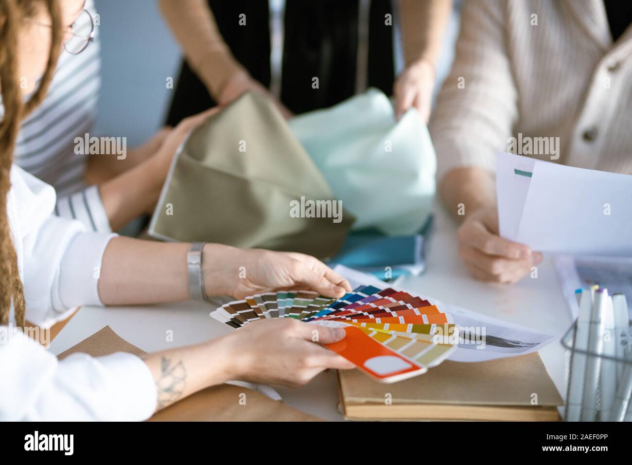Mains de designer holding la palette de plus de 24 tout en travaillant avec des collègues Banque D'Images