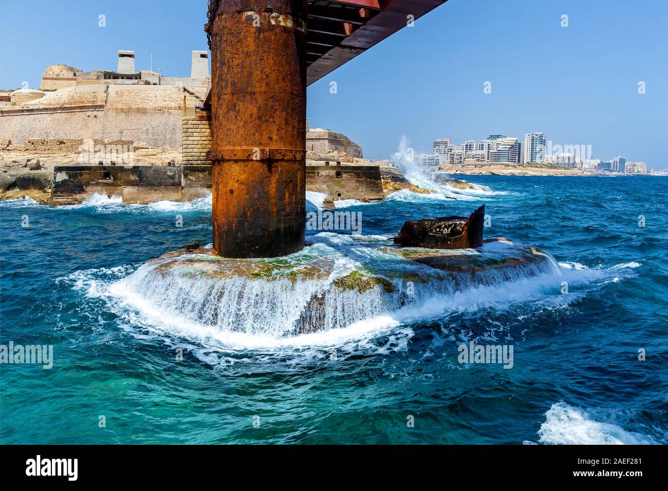 Les vagues turquoises de la mer Méditerranée sont de s'écraser dans le support métallique du Pont St Elme à Malte, La Valette. Banque D'Images