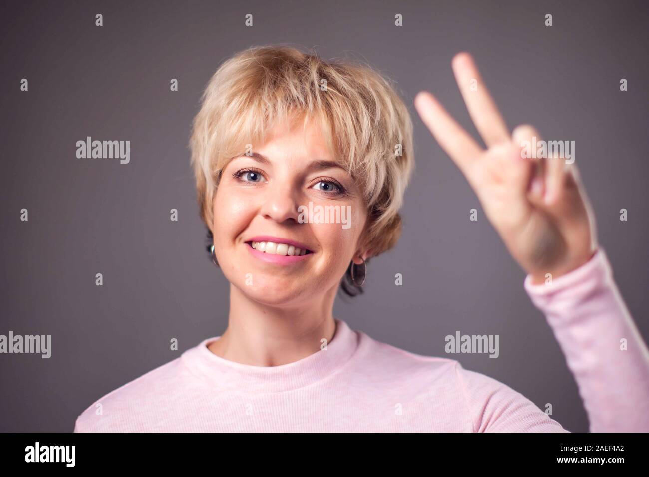 Femme avec de courts cheveux blonds montrant bon geste. Les gens et les émotions concept Banque D'Images