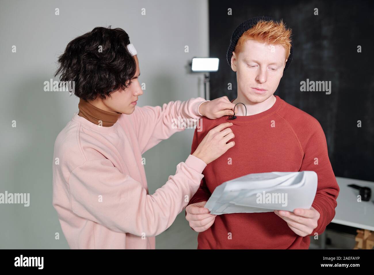 Casual guy noir avec les cheveux ondulés mettre le microphone sur le sweatshirt de vlogger Banque D'Images