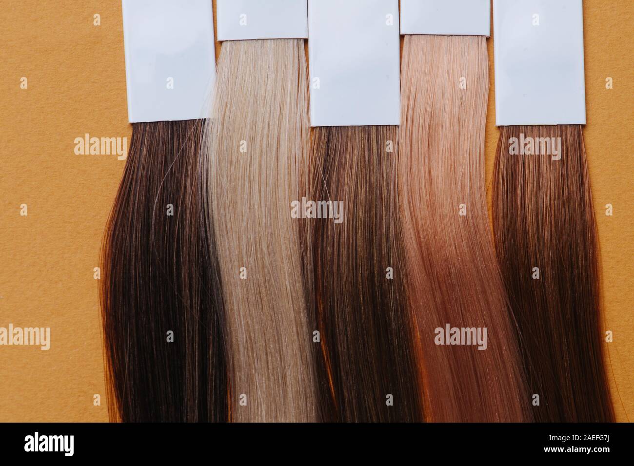 Close up image des écluses de cheveux teints. Les échantillons dans une rangée sur l'orange. Banque D'Images