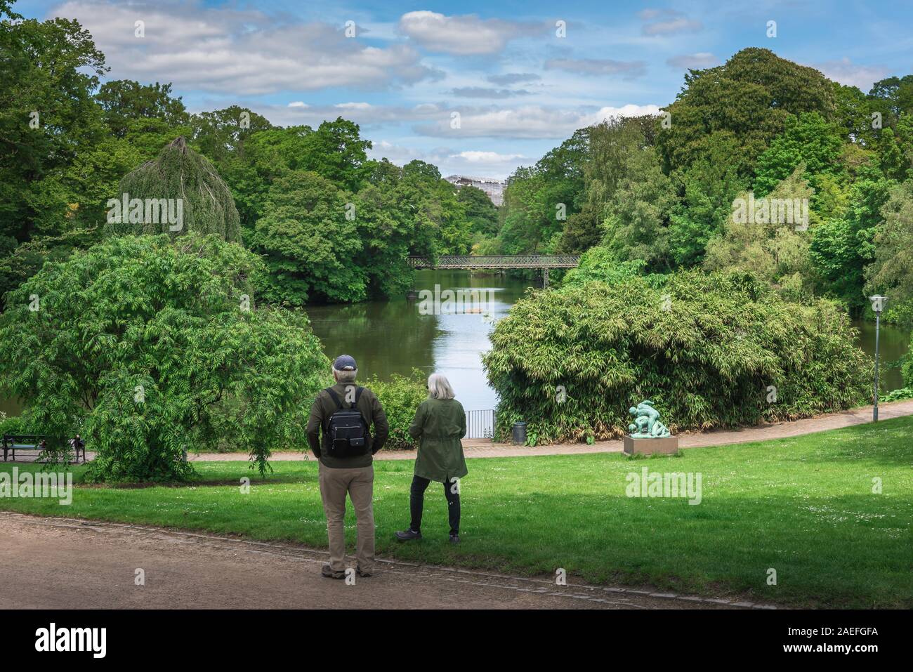 Couple mature park, rear view of a young couple s'arrêter pour regarder le lac en Ørstedsparken, un parc public dans le centre de Copenhague, au Danemark. Banque D'Images