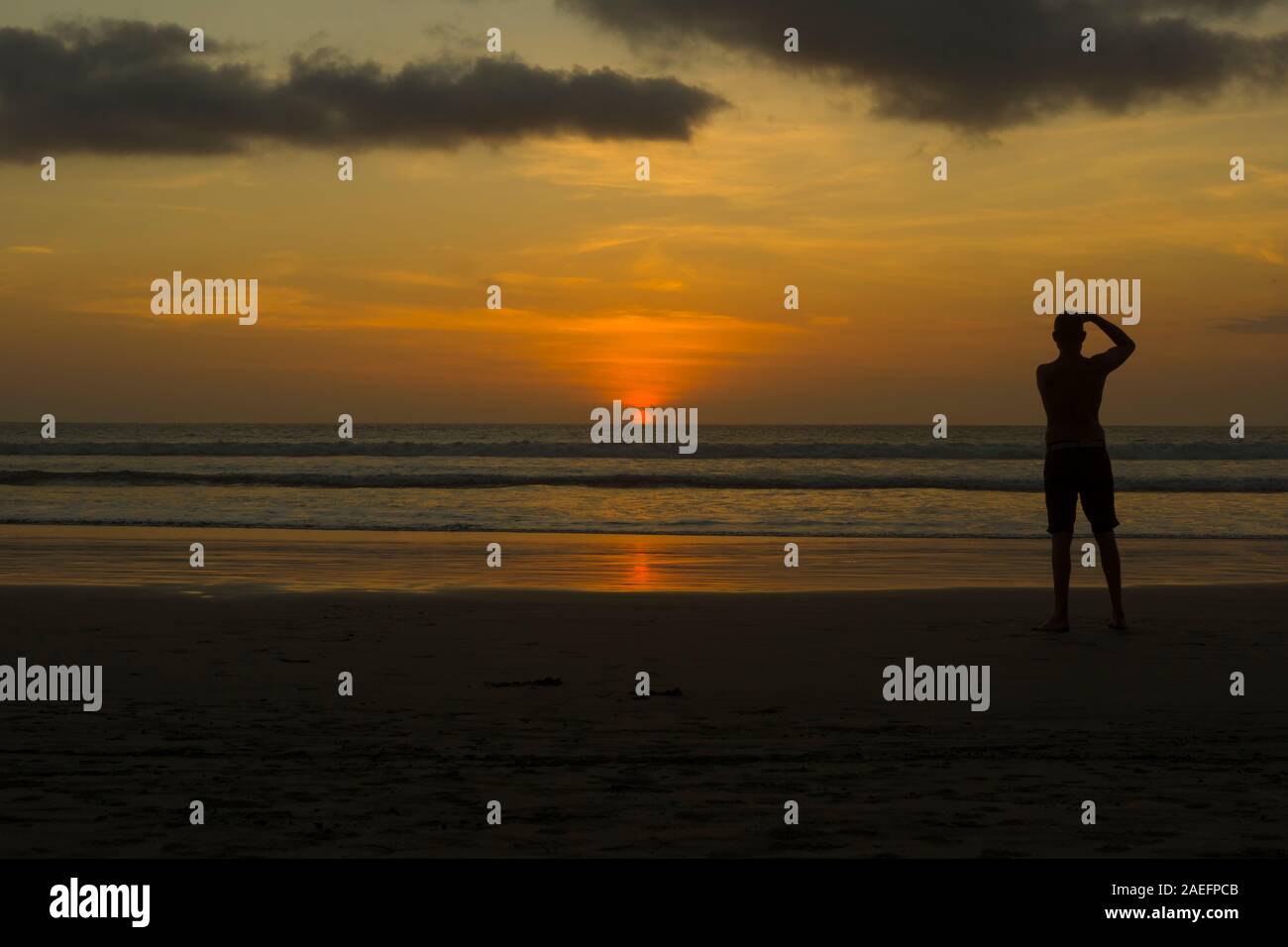 Coucher du soleil doré à Kuta Beach avec la silhouette d'un photographe de prendre une photo au coucher du soleil Banque D'Images