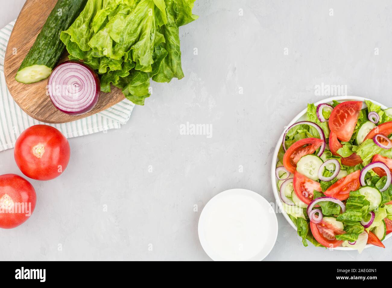 Plat végétarien sain, une salade de légumes avec de la tomate, le concombre, la laitue, l'oignon rouge sur fond de béton gris. Menu de régime. Vue d'en haut. Télévision lay, m Banque D'Images