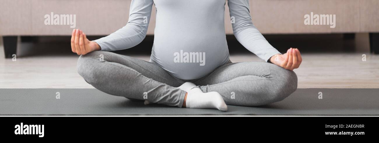 Portrait de femme enceinte millénaire meditating on yoga mat Banque D'Images