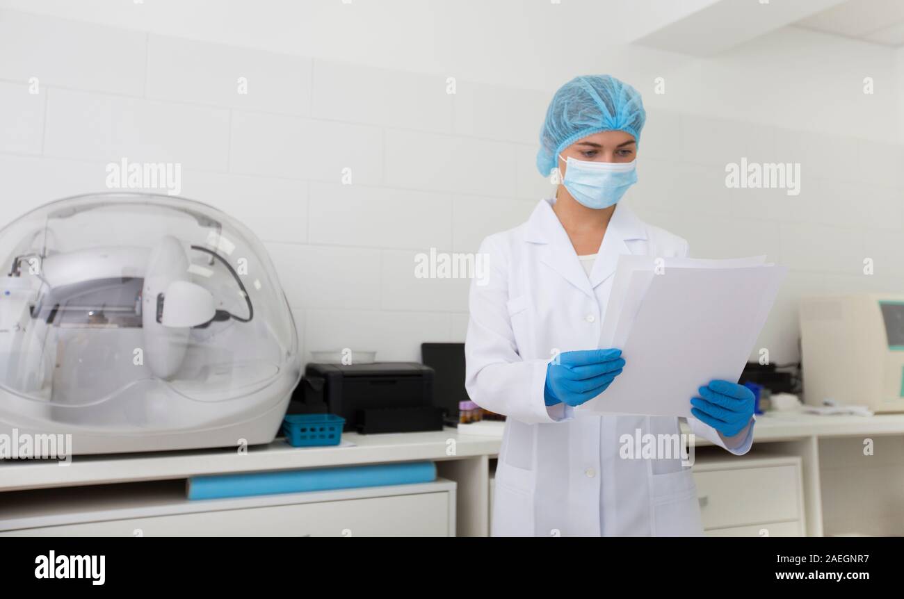Cheerful assistant en masque de protection et des gants de sécurité lecture in lab Banque D'Images