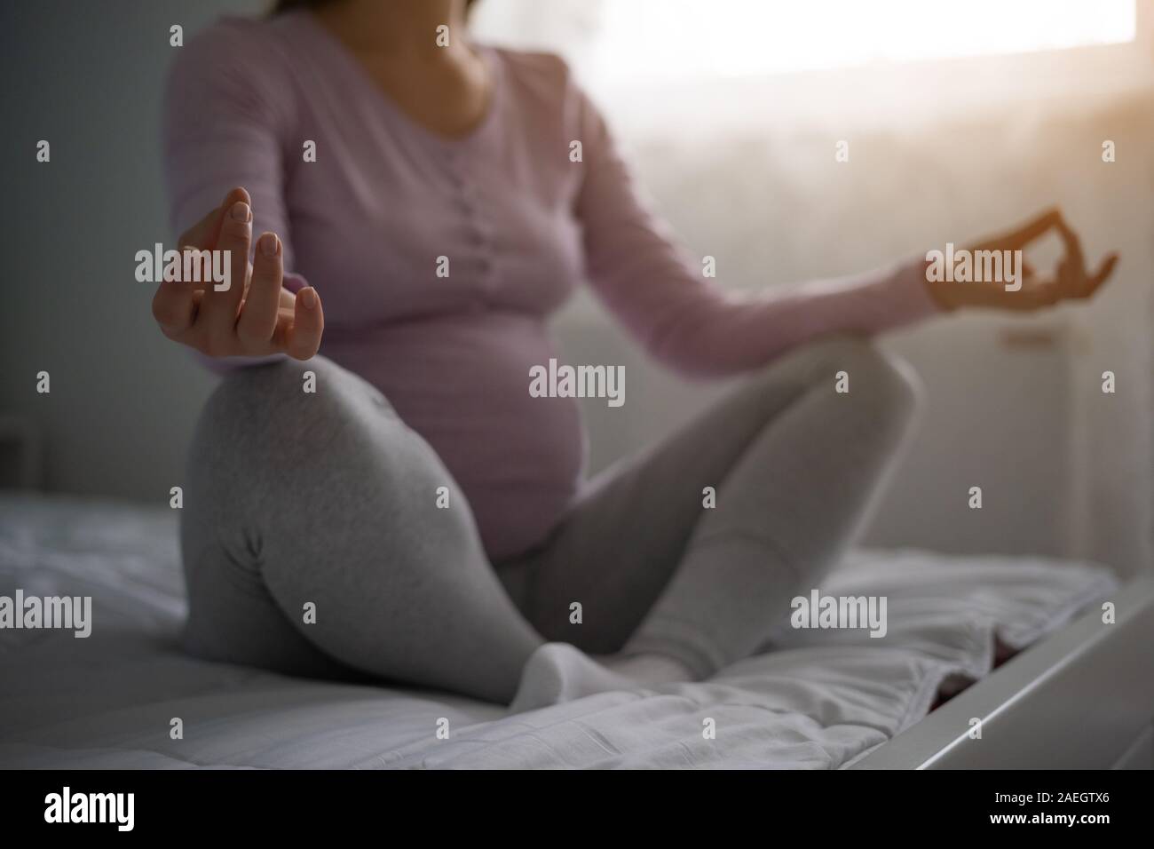 Pregnant woman meditating at home. Position du Lotus. Banque D'Images