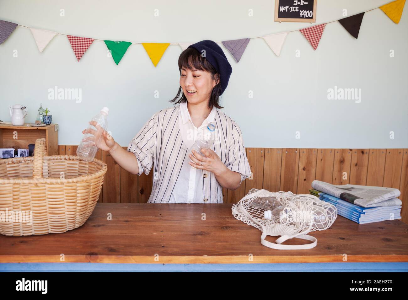 Japanese woman standing in a farm shop, le tri des bouteilles en plastique transparent en panier. Banque D'Images