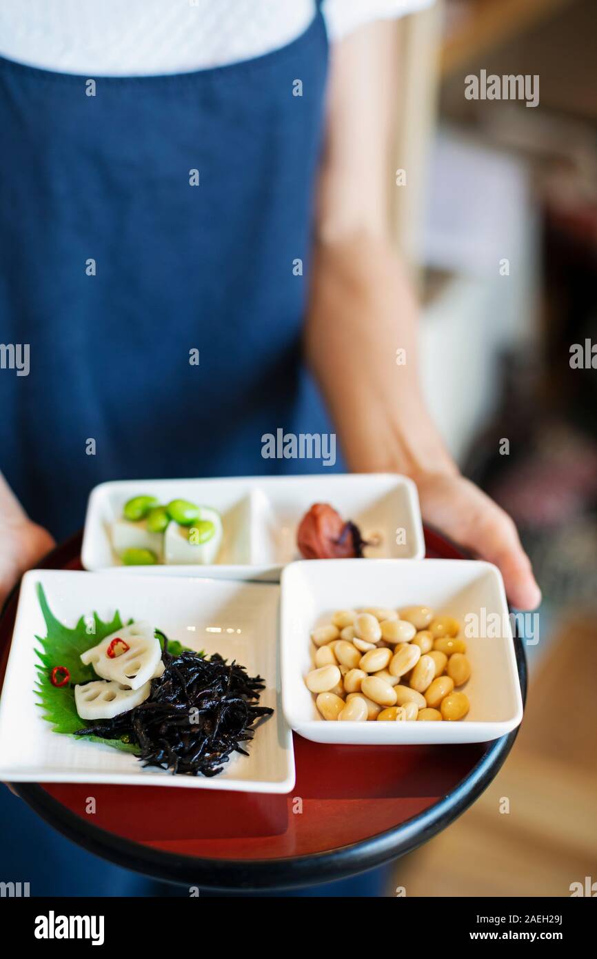 High angle portrait of waitress holding une sélection de plats végétariens aliments japonais dans un café. Banque D'Images