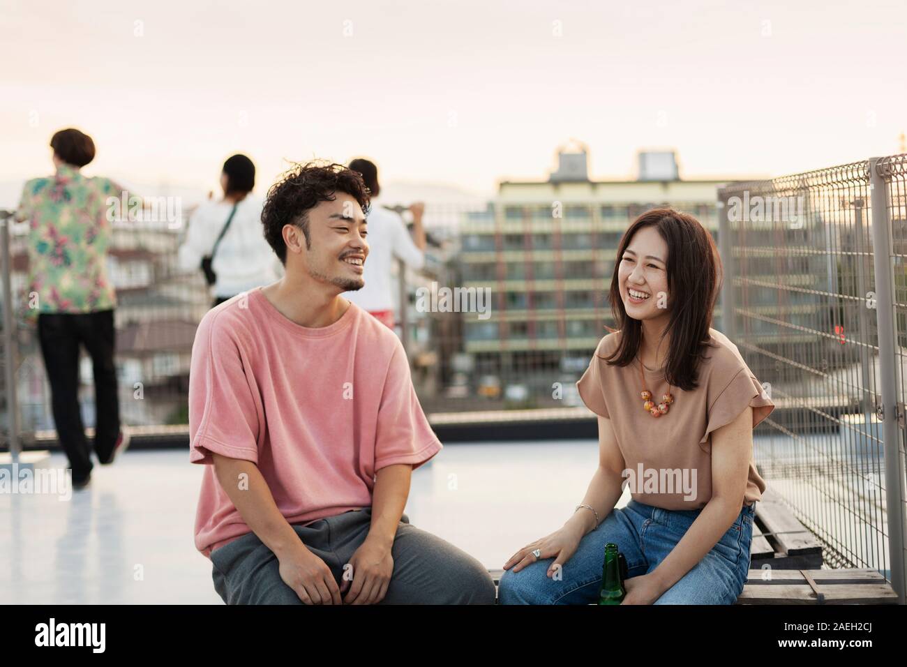 Jeune homme japonais et femme assise sur un toit dans un milieu urbain. Banque D'Images