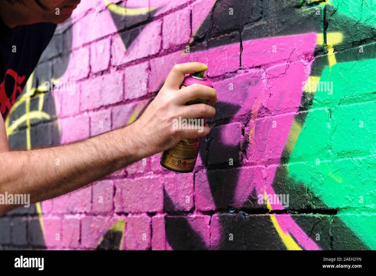 Artiste de graffiti masculin restant son propre dessin sur un noir mur Banque D'Images