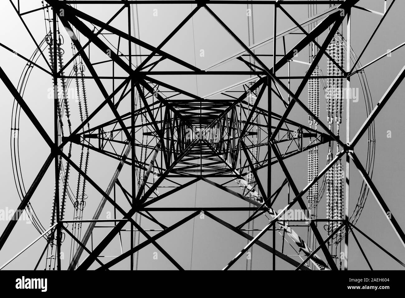 Photo en noir et blanc de pylônes et de câbles d'électricité silhouetté contre le ciel sans nuages avec des lignes directrices Banque D'Images