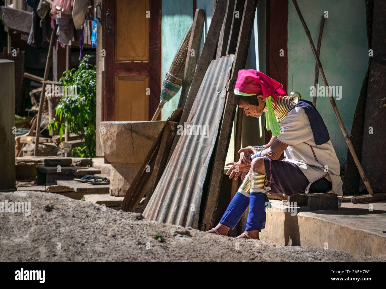 Une femme de la tribu Kayan âgées portant tenue traditionnelle assise sur son porche Maison dans village Pet Pan, le Myanmar. Banque D'Images
