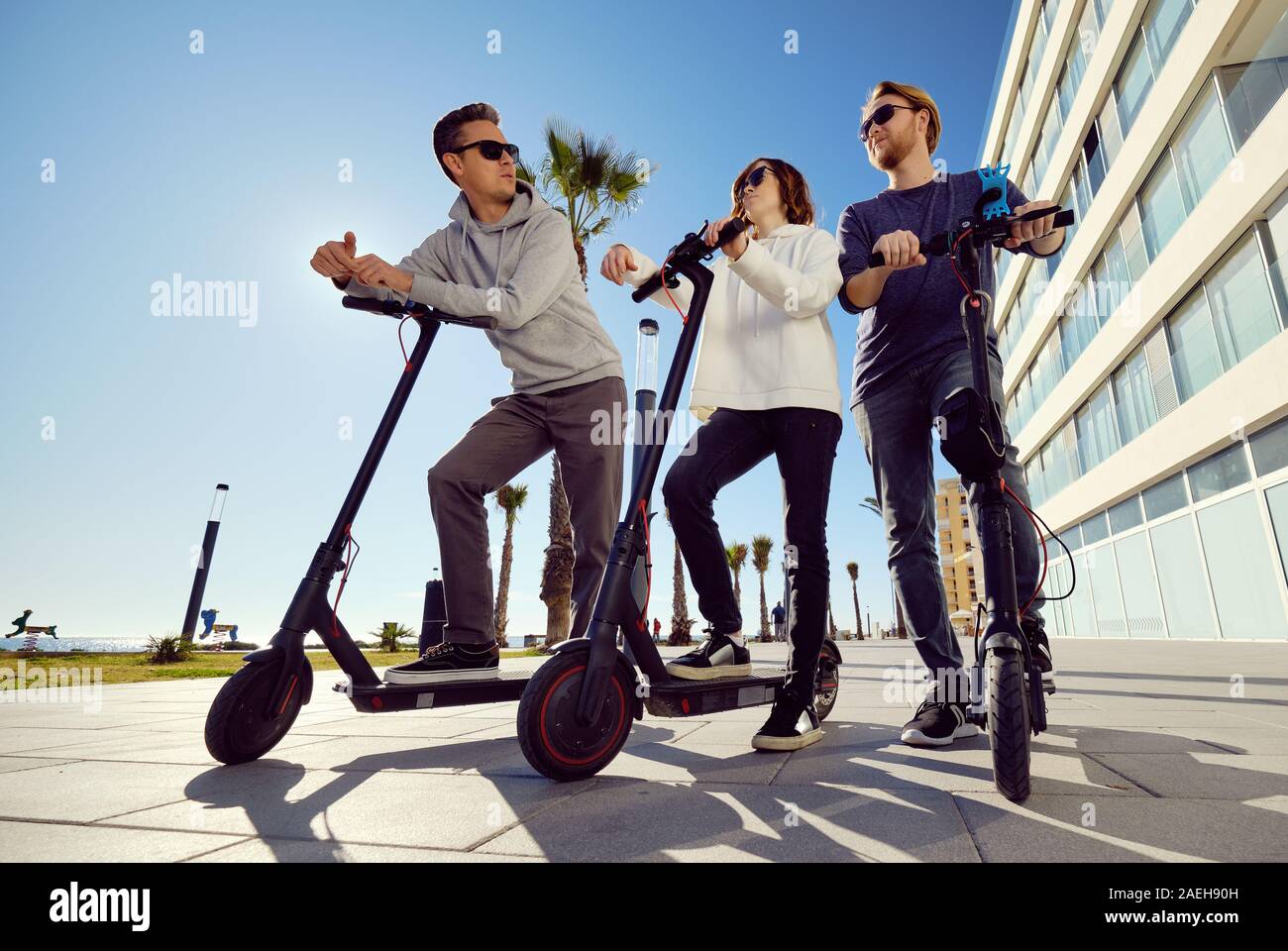 Trois meilleurs amis jeunes de 20 ans à 30 ans, fille et gars passent du temps à l'extérieur réunis ensemble à conduire sur un scooter électrique moderne véhicule terrestre Banque D'Images