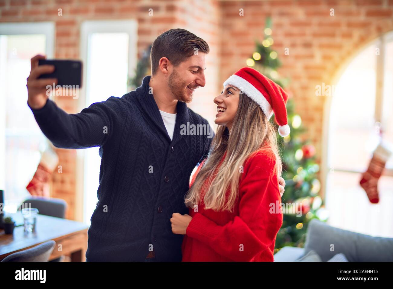 Jeune beau couple souriant heureux et confiant. Comité permanent et s'étreindre par caméra autour de selfies arbre de Noël à la maison Banque D'Images