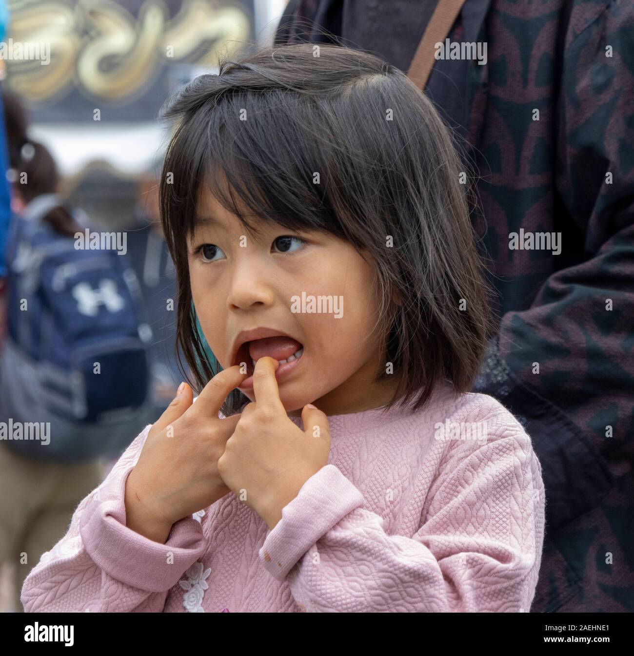 Japanese girl making a face en tirant sur sa bouche, Tokyo, Japon Banque D'Images