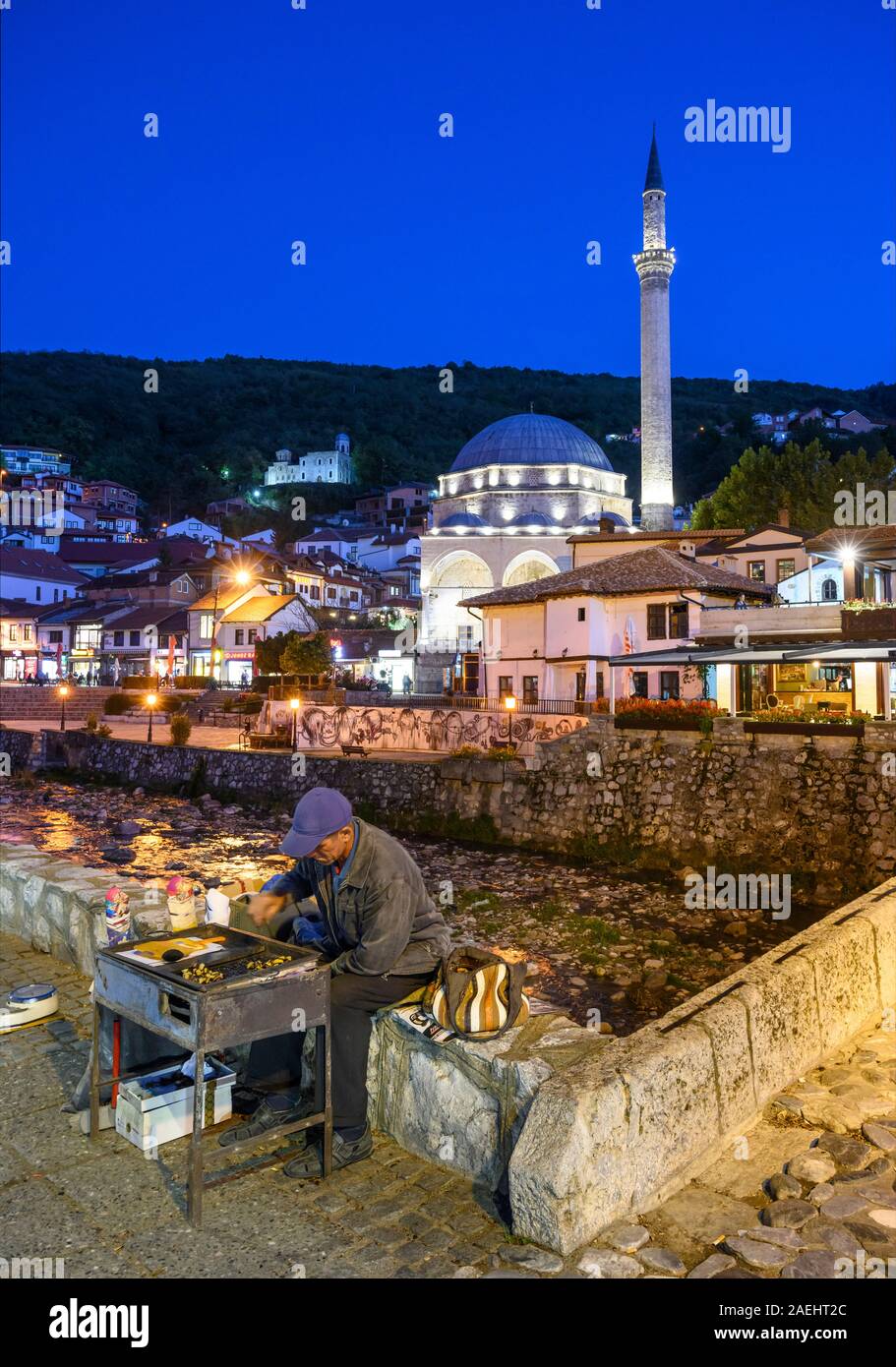 Par le vendeur de marrons chauds de la rivière Bistrica avec la vieille ville de Prizren et la mosquée de Sinan Pacha en arrière-plan. Au Kosovo, Balkans central. Banque D'Images