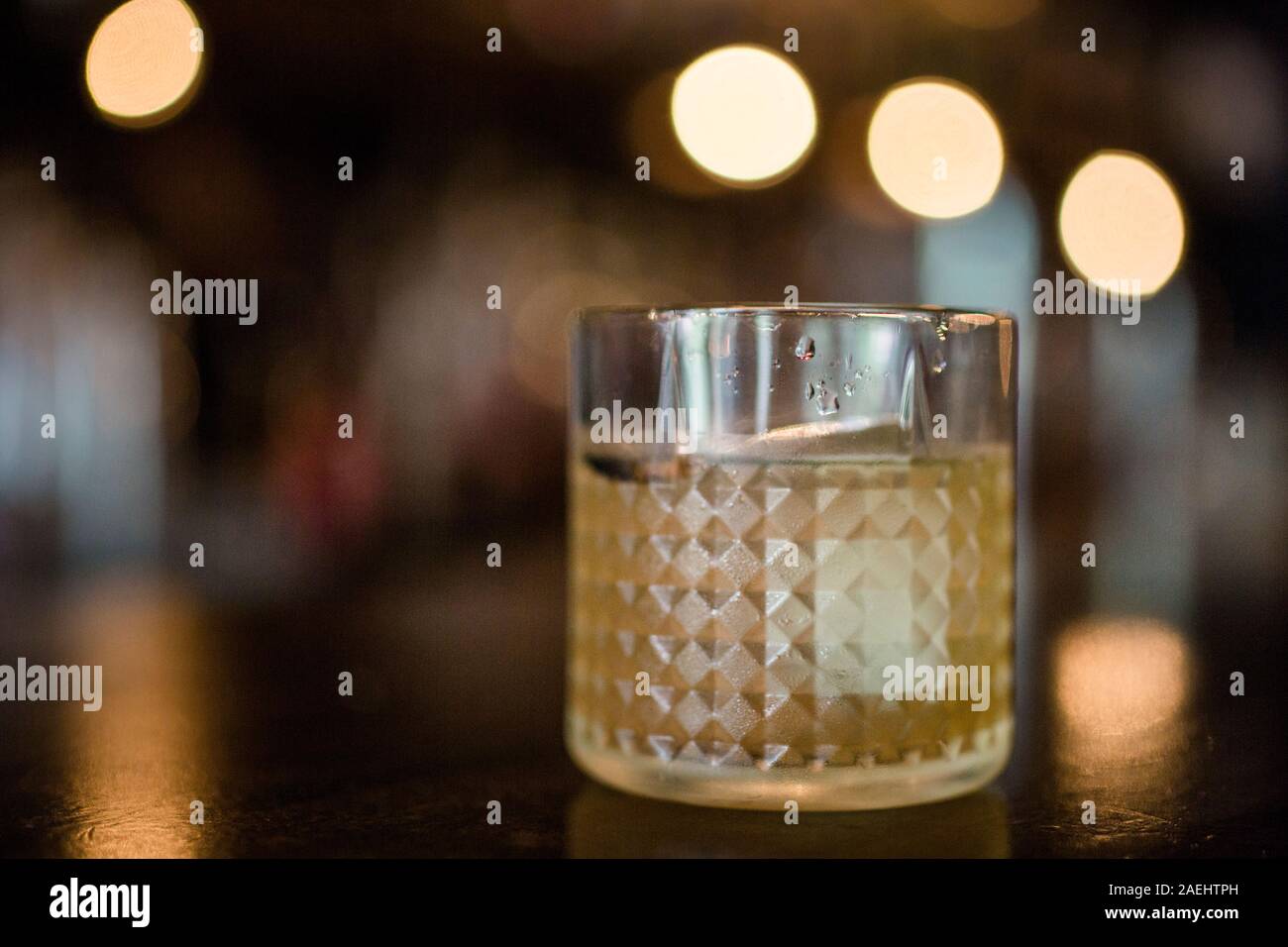 Un grand verre rimed avec condensation est assis sur une table dans la lumière d'or Banque D'Images
