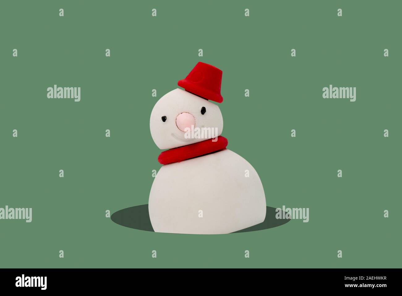 Bonhomme de neige hors du trou sur fond vert, concept minimal de vacances de noël. Banque D'Images