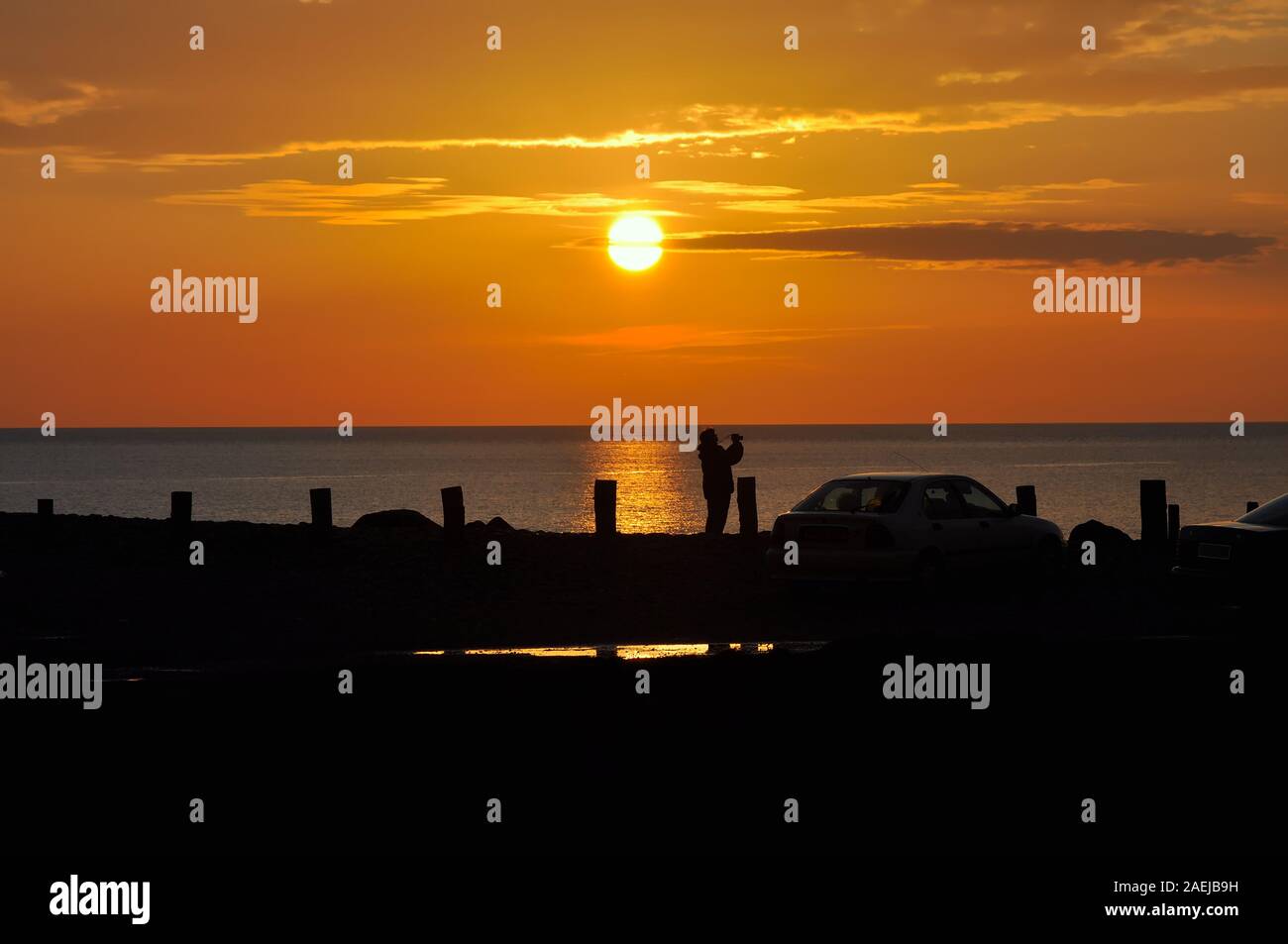 Photographe en silhouette prendre une photo d'un glorieux coucher de soleil sur la mer d'Irlande à Aberystwyth Ceredigion Pays de Galles UK Banque D'Images