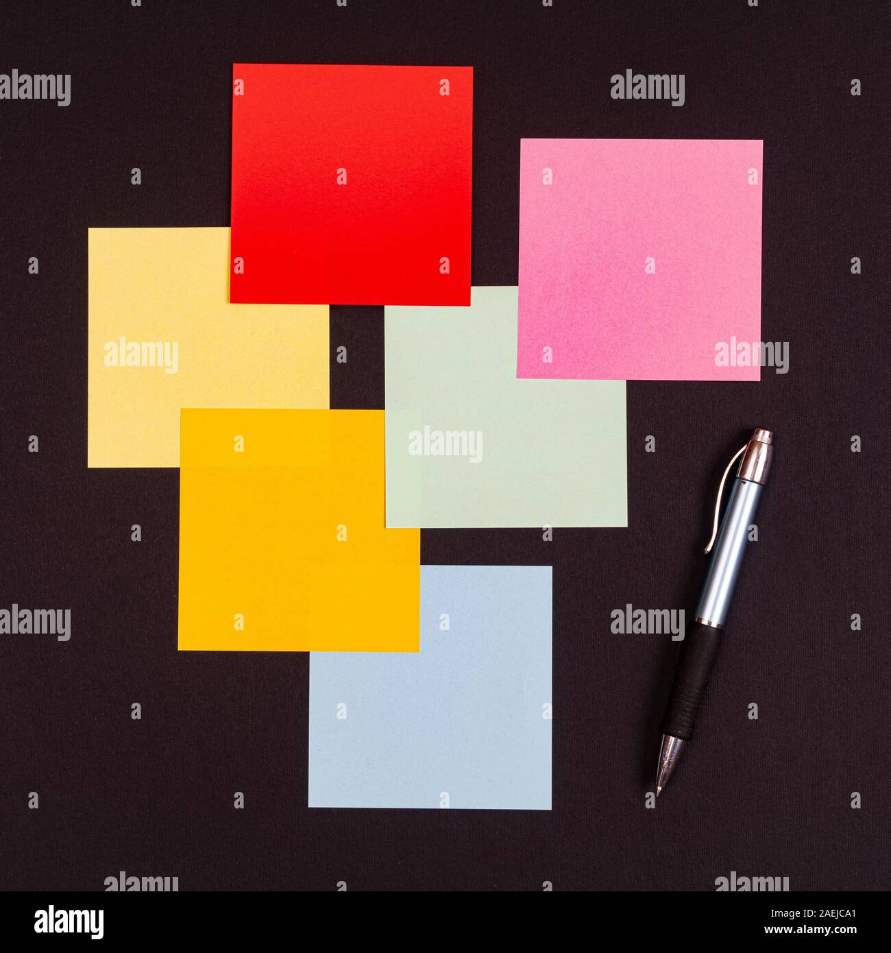 Quelques feuilles de couleur pour les notes et un stylo sur une surface noire Banque D'Images