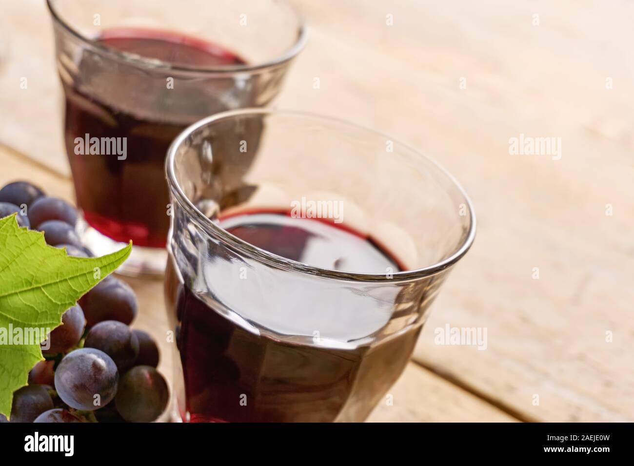 Deux verres à vin sans pied sur une table remplie de vin rouge, bleu et vert raisin grape leaf. Angle néerlandais abattu avec focus sélectif. Banque D'Images