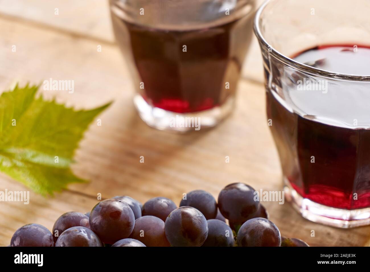 Deux verres à vin sans pied sur une table remplie de vin rouge, bleu et vert raisin grape leaf. Coup horizontal avec focus sélectif. Banque D'Images