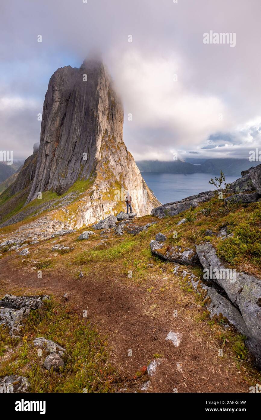 Voyageur solitaire et une vue depuis le mont Hesten sur la montagne emblématique Segla à la lumière de l'epic sunsetcovered dans le brouillard et de montagnes en arrière-plan, Fjordga Banque D'Images