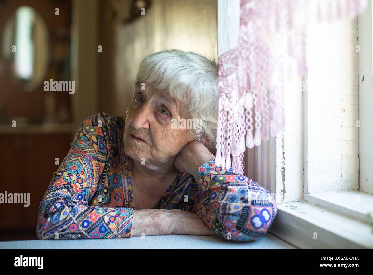Portrait d'une vieille femme assise à une table dans la sa maison. Banque D'Images