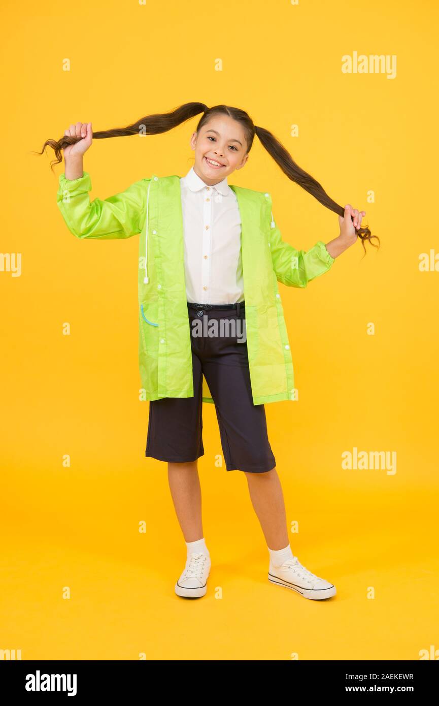 Concept étanche. Adorable enfant. Heureux lycéenne porter imperméable sur fond jaune. Petite lycéenne porter des vêtements résistant à l'eau pour jour de pluie. Jolie lycéenne se sentent protégés pour le printemps. Banque D'Images