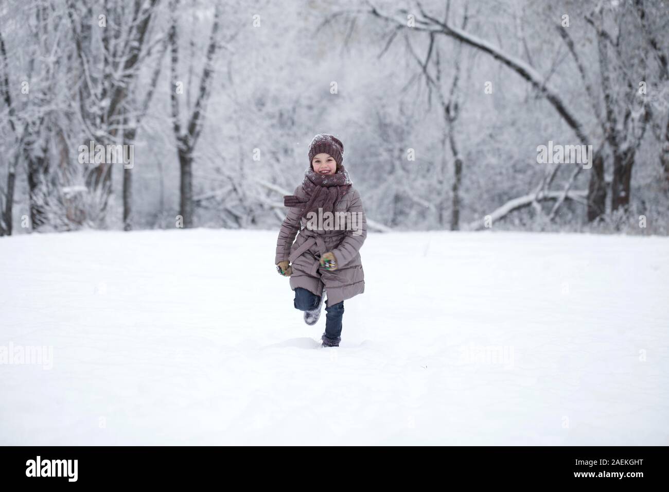 Fille dans des vêtements d'hiver court à travers prés enneigés en hiver Banque D'Images