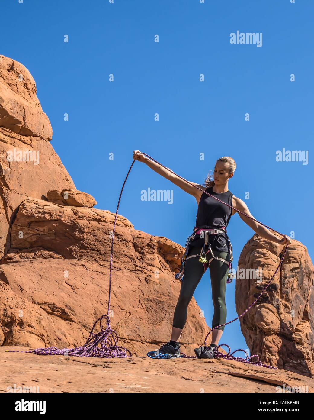 Une jolie jeune femme se prépare à une escalade dans le jardin d'Éden dans Arches National Park près de Moab, Utah. Banque D'Images
