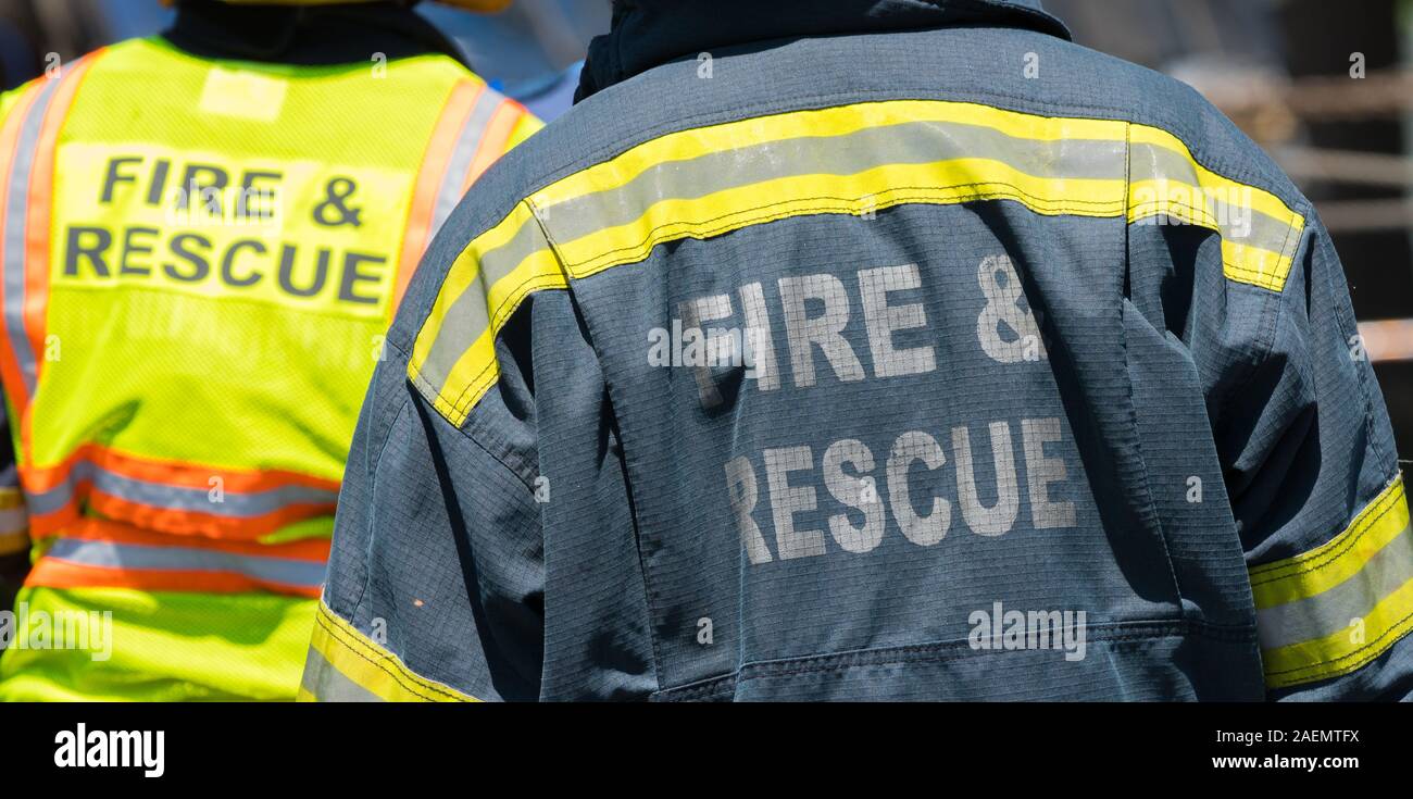 Deux ou une paire de pompiers ou pompiers lors d'une scène d'incendie et de secours portant des vêtements haute visibilité à l'extérieur Banque D'Images