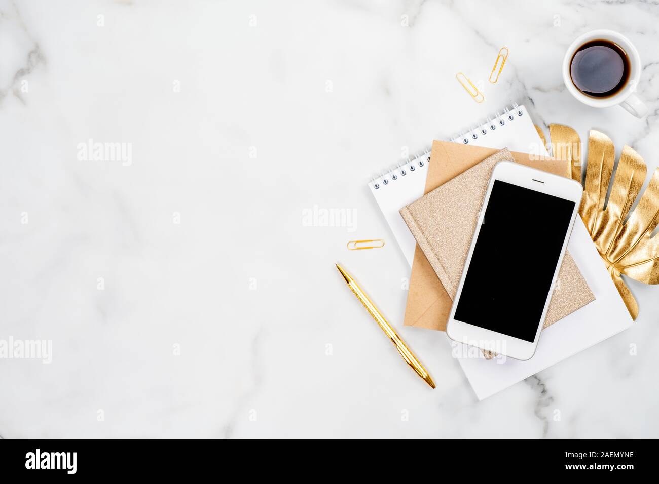 24 Bureau d'accueil élégant avec smartphone, tasse de café, le bloc-notes, papier et stylo d'or feuille tropicale monstera. Mise à plat, vue du dessus, copiez l'espace. Feminin Banque D'Images