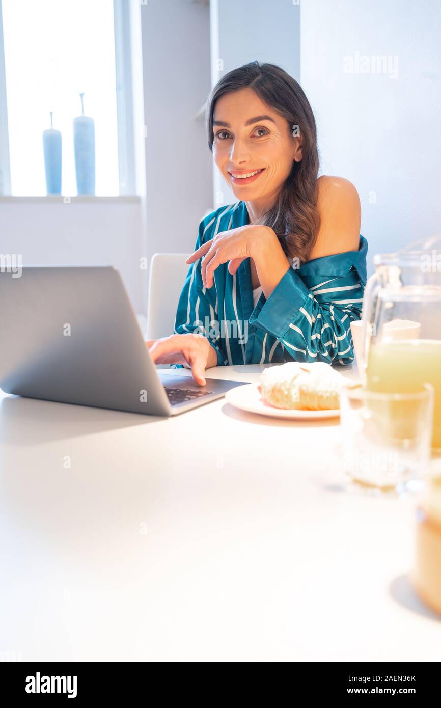 Le petit-déjeuner et dame souriant à l'aide d'ordinateur portable stock photo Banque D'Images