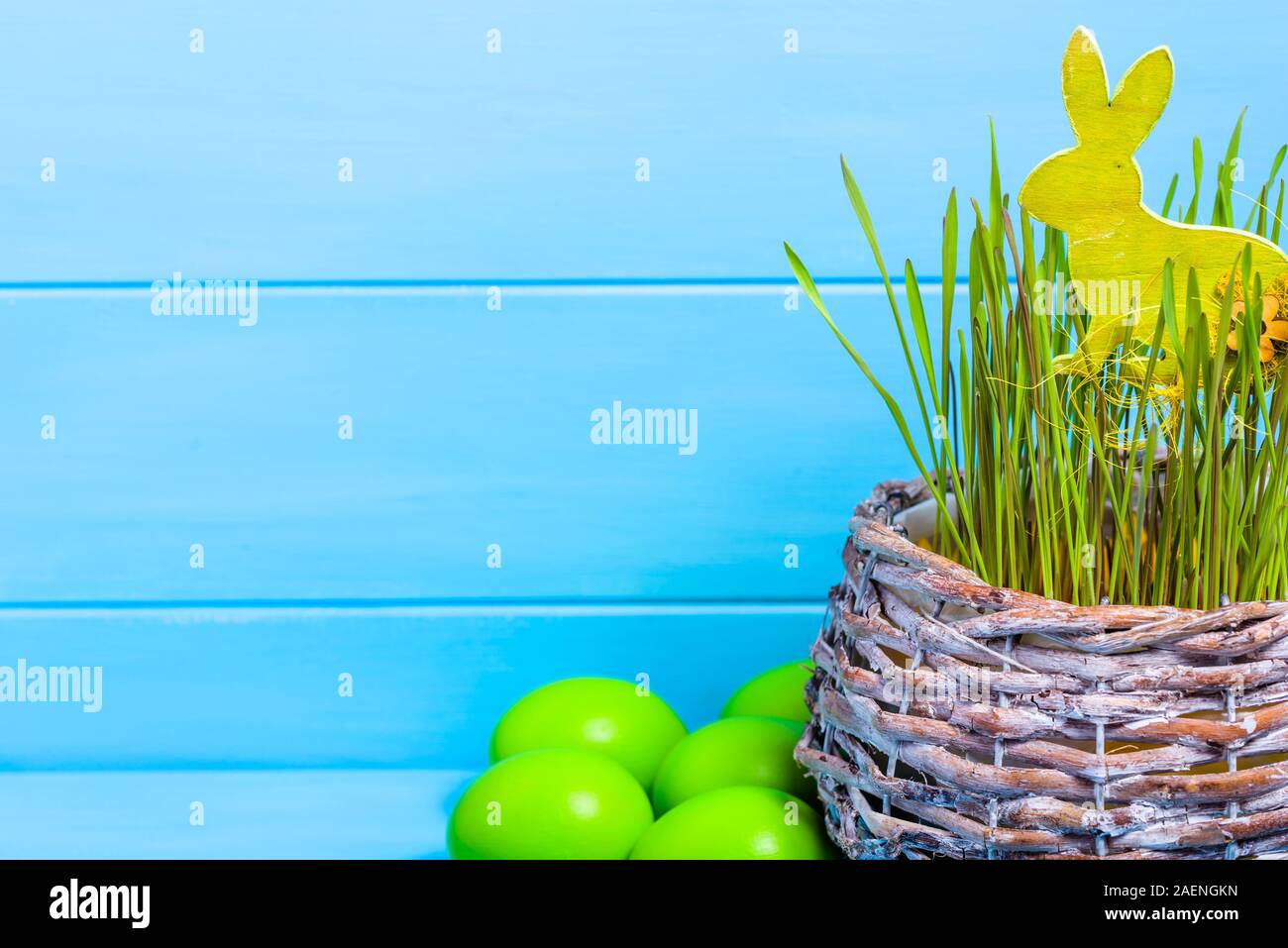 Arrière-plan de Pâques avec des œufs verts et lapin de Pâques dans l'herbe, le blé vert frais dans le panier Banque D'Images