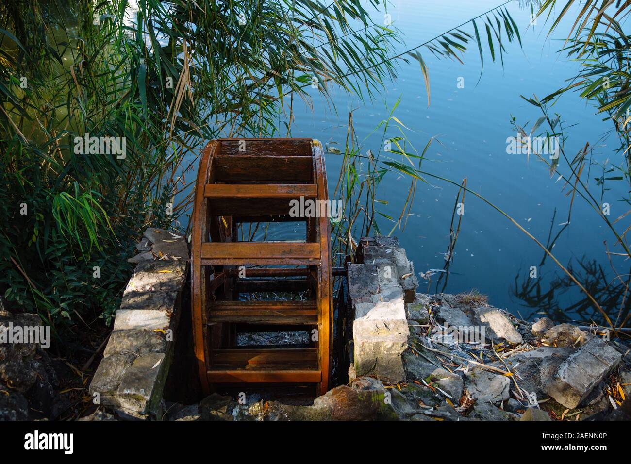 La vieille roue à eau est situé sur le lac entouré d'arbres et de pierres sur une journée ensoleillée. Banque D'Images