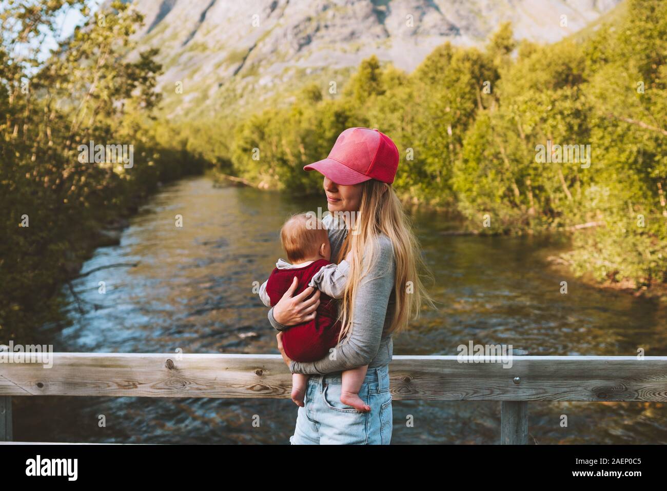 Mère avec enfant marche à river dans les montagnes famille voyageant de vie sain jeune femme maman holding baby summer vacations de jour de mères en plein air Banque D'Images
