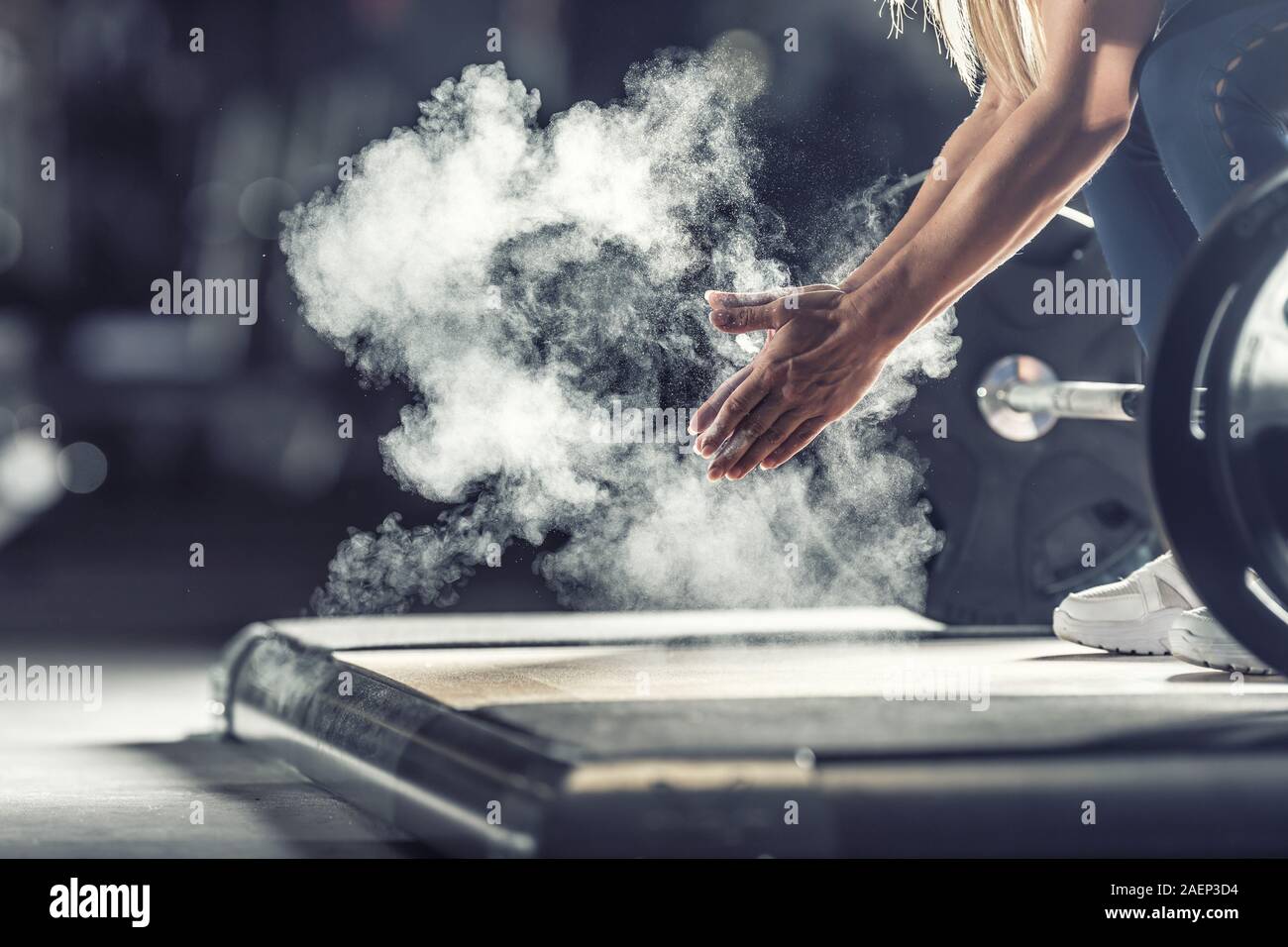 Femme haltérophile musculaire des mains les mains avant d'entraînement d'haltères à la salle de sport avec haltères. Banque D'Images