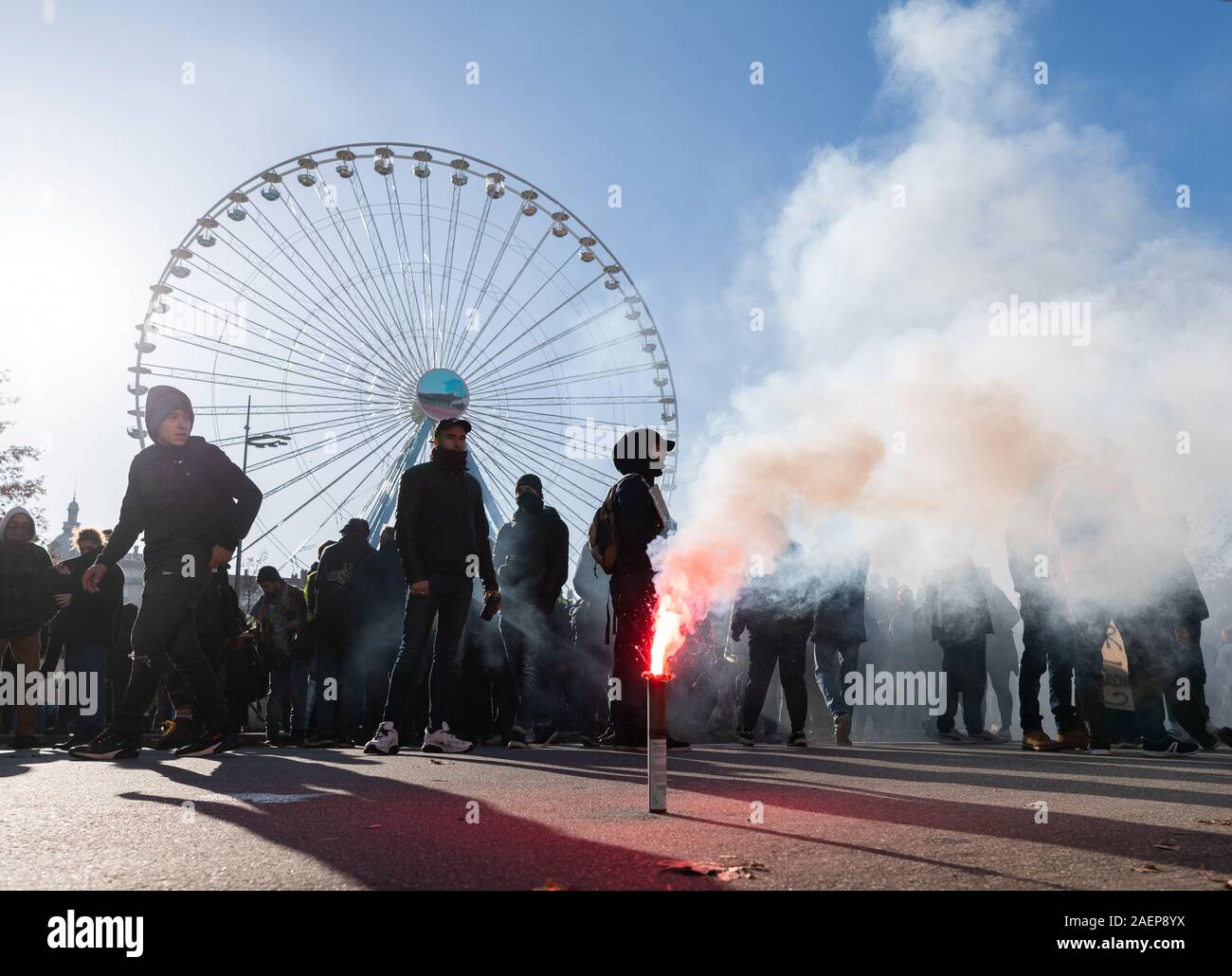 Lyon, France. Dec 10, 2019. La Pyrotechnie burns lors d'une manifestation dans le cadre de grèves et manifestations contre la réforme des retraites en France à la place Bellecour. La grève générale et des manifestations violentes à Lyon également conserver les fans de l'équipe de football Bundesliga RB Leipzig sur leurs orteils. À midi, le mardi, le club a mis en garde ses partisans de ne pas répondre à la Place Bellecour pour un entraînement commun pour le stade. Peu de temps après, il y a eu des affrontements entre manifestants et policiers sur et autour de la place. Les canons à eau et des gaz lacrymogènes ont été utilisés, les hélicoptères de l'encerclé paysage. Credit : dpa Banque D'Images