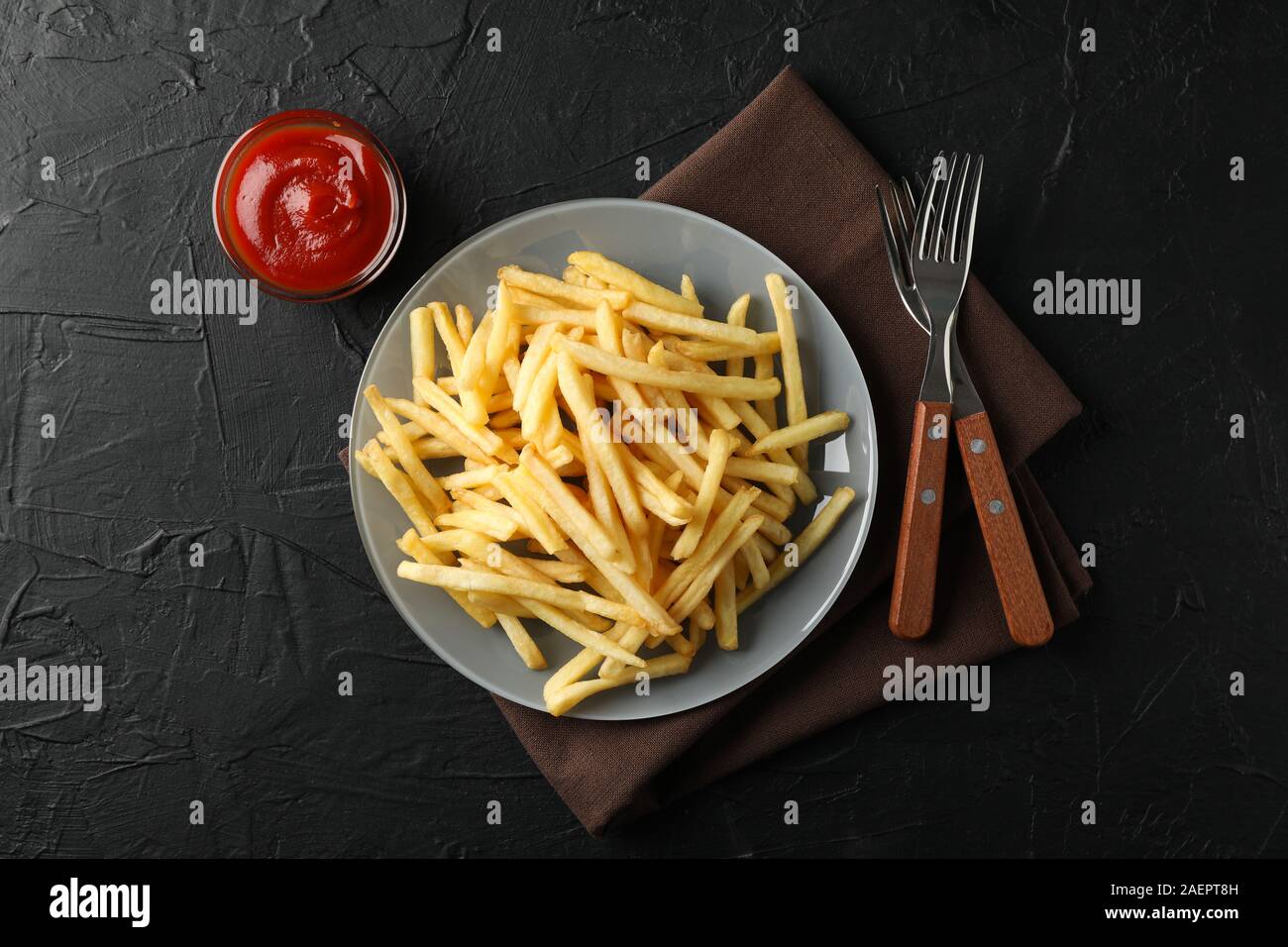 Assiette de frites, sauce rouge, serviette, fourches sur fond noir, de l'espace pour le texte. Vue d'en haut Banque D'Images